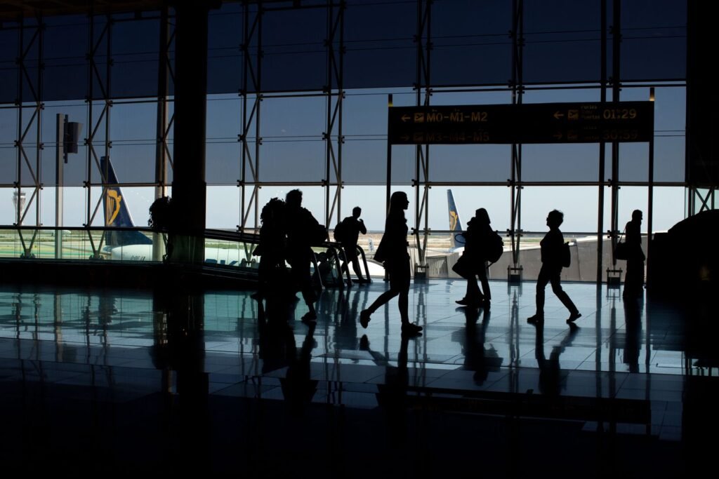 Silhouettes of travelers walking through an airport terminal