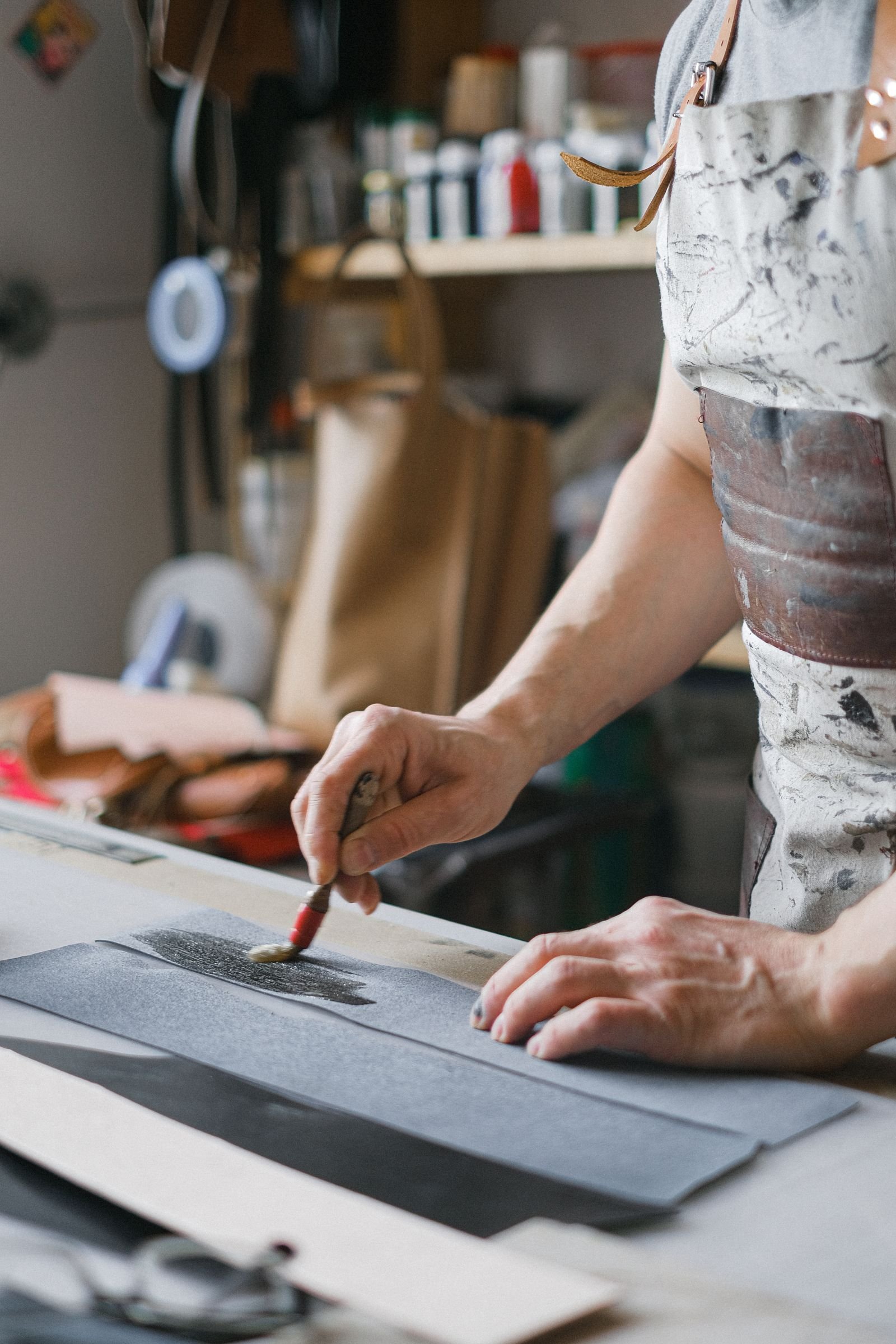 Focused artisan brushing leather in a workshop, highlighting craftsmanship