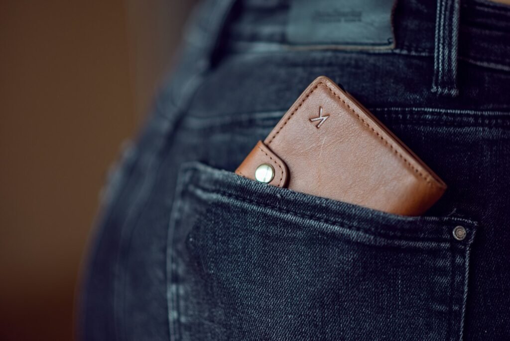 Black leather wallet resting on blue denim jeans