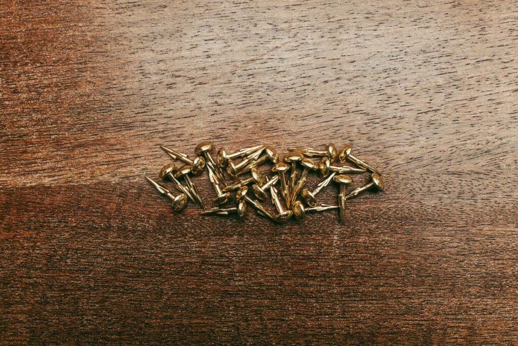 Detailed close-up of brass tacks scattered on a wooden surface