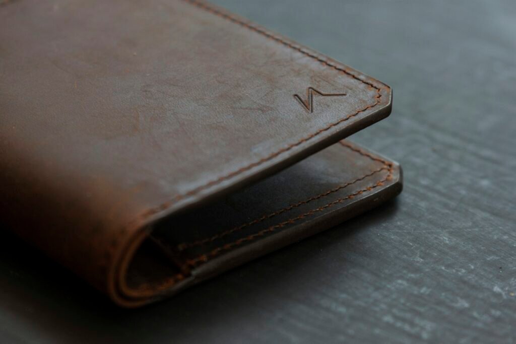 Brown leather bifold wallet resting on a wooden table