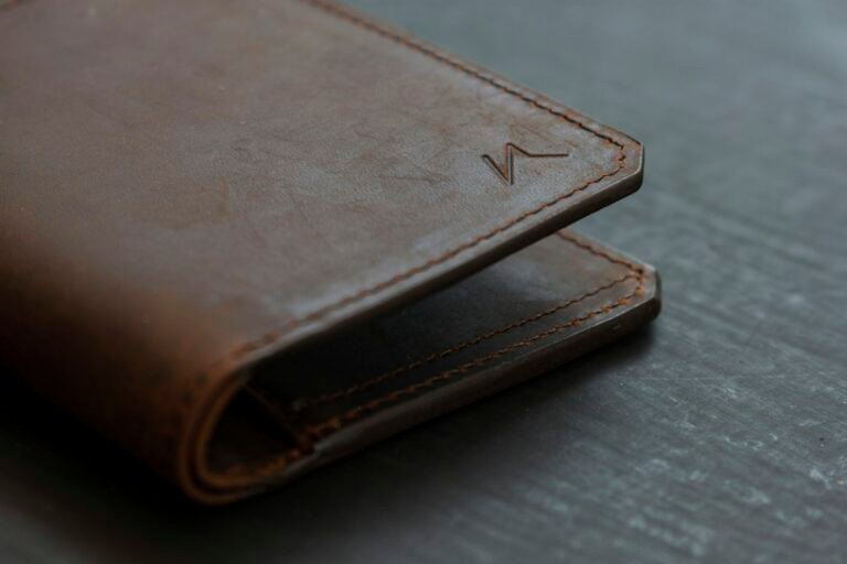 Brown leather bifold wallet resting on a wooden table