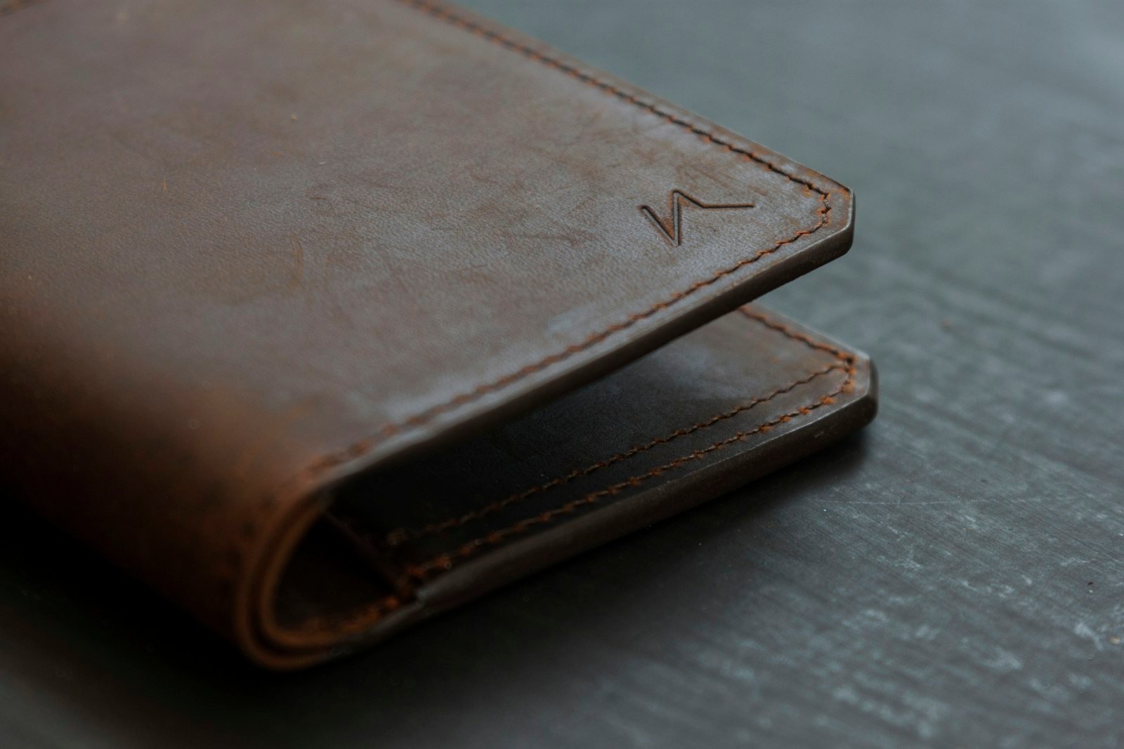 Brown leather bifold wallet resting on a wooden table