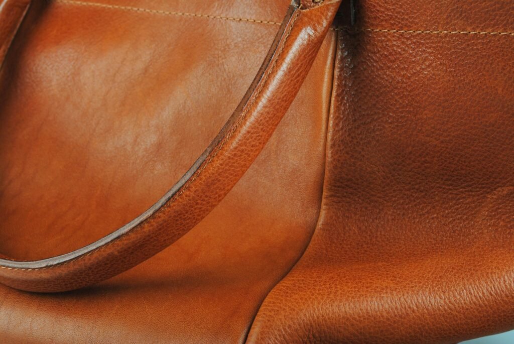 Brown leather handbag with a long strap showing natural worn patina