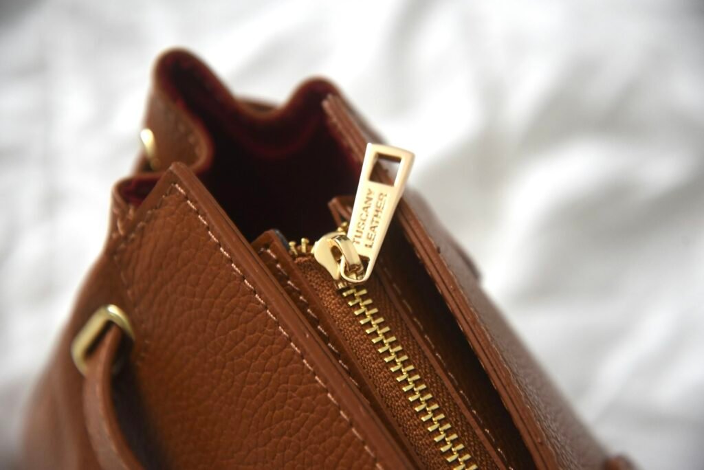 Close-up of a brown leather handbag zipper and hardware