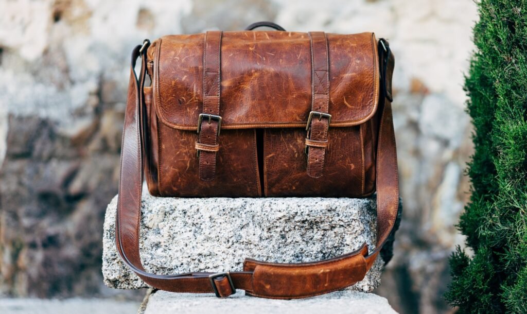 Brown leather satchel bag resting on a gray concrete surface