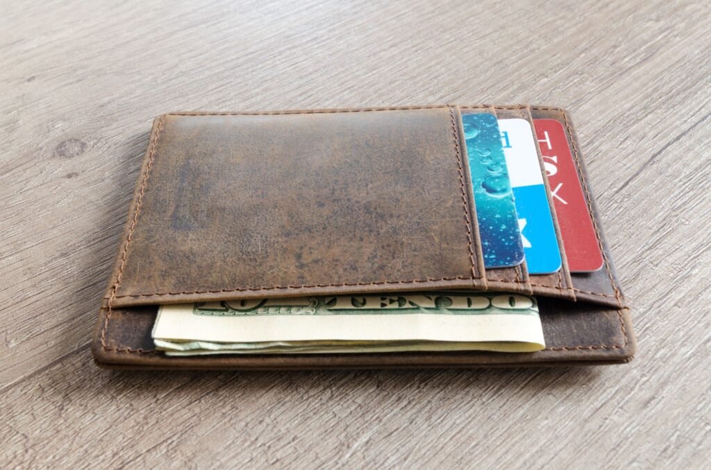 Brown leather wallet with cash and credit cards on a wooden table