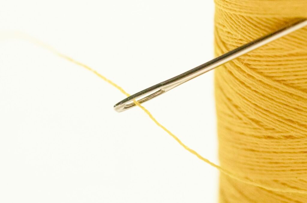 Brown thread with a gray needle used for leather repair stitching