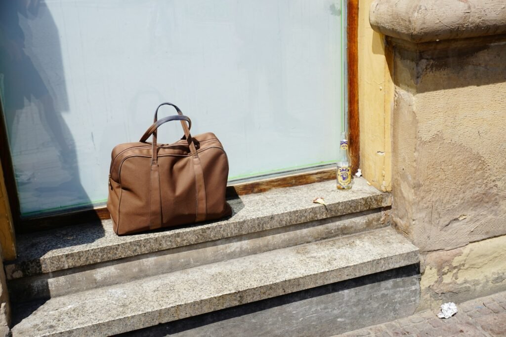 Brown leather travel bag resting on stone steps outside a building