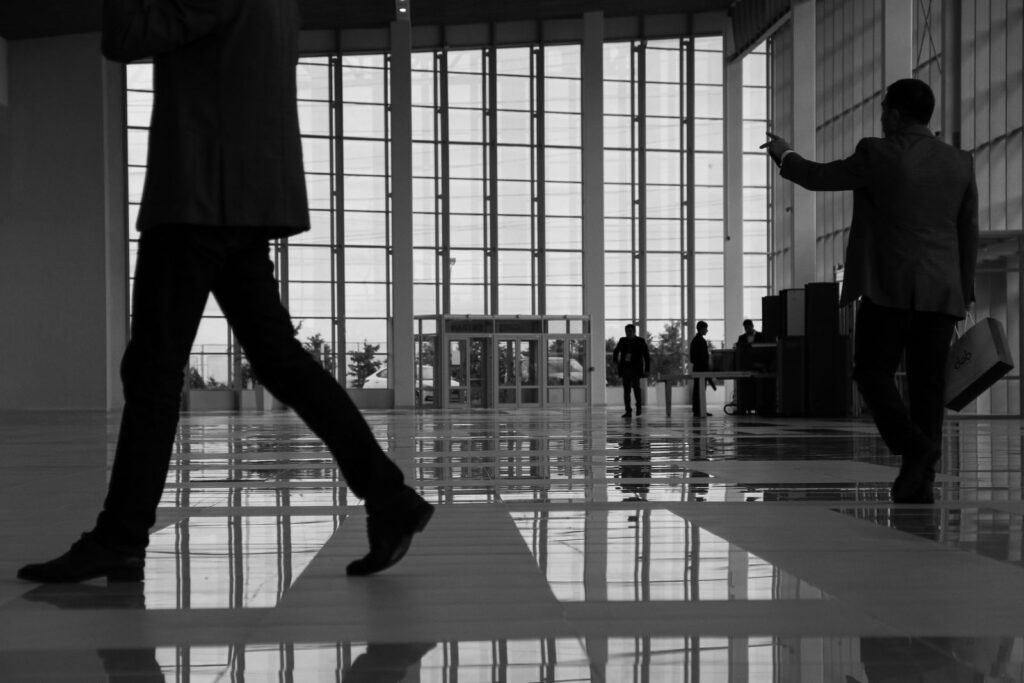 Business professionals walk through a modern, glass-paneled office lobby