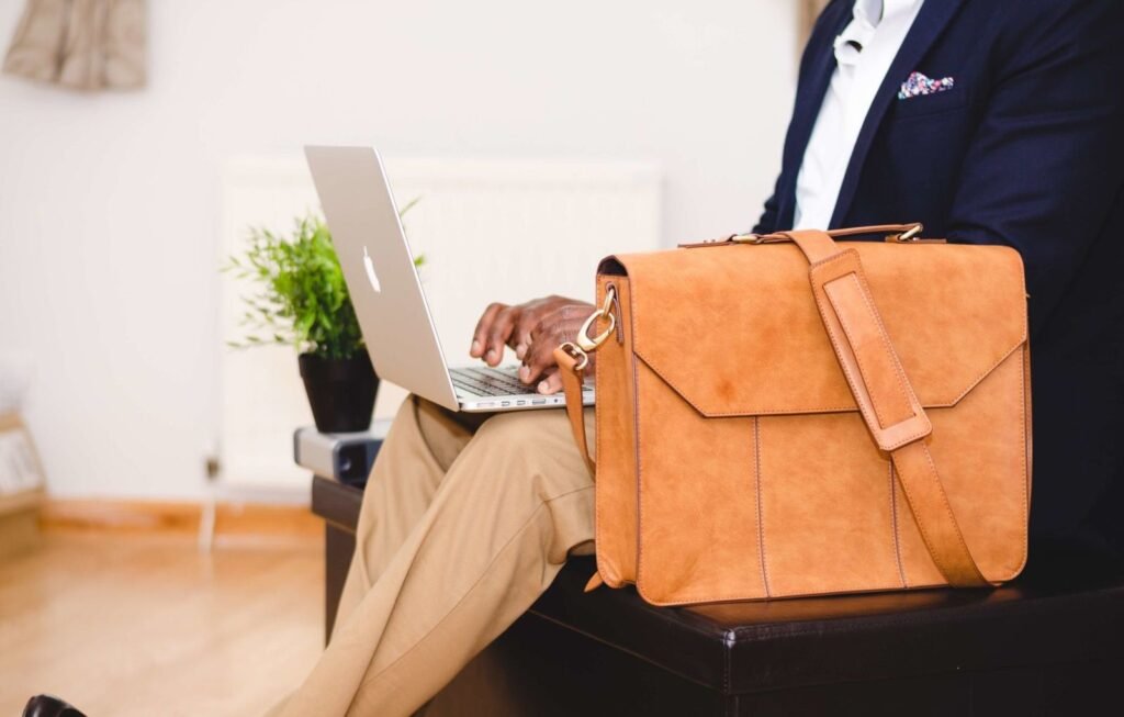 Stylish businessman working on a laptop indoors with a leather bag nearby