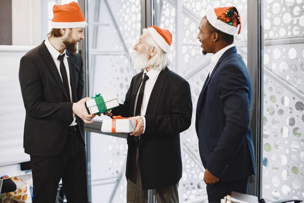 Three businessmen in Santa hats exchanging gifts in a festive office setting
