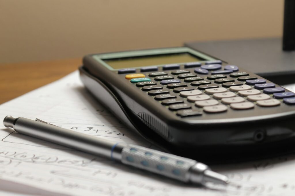 Calculator and pen sitting on top of a piece of paper for a cost decision