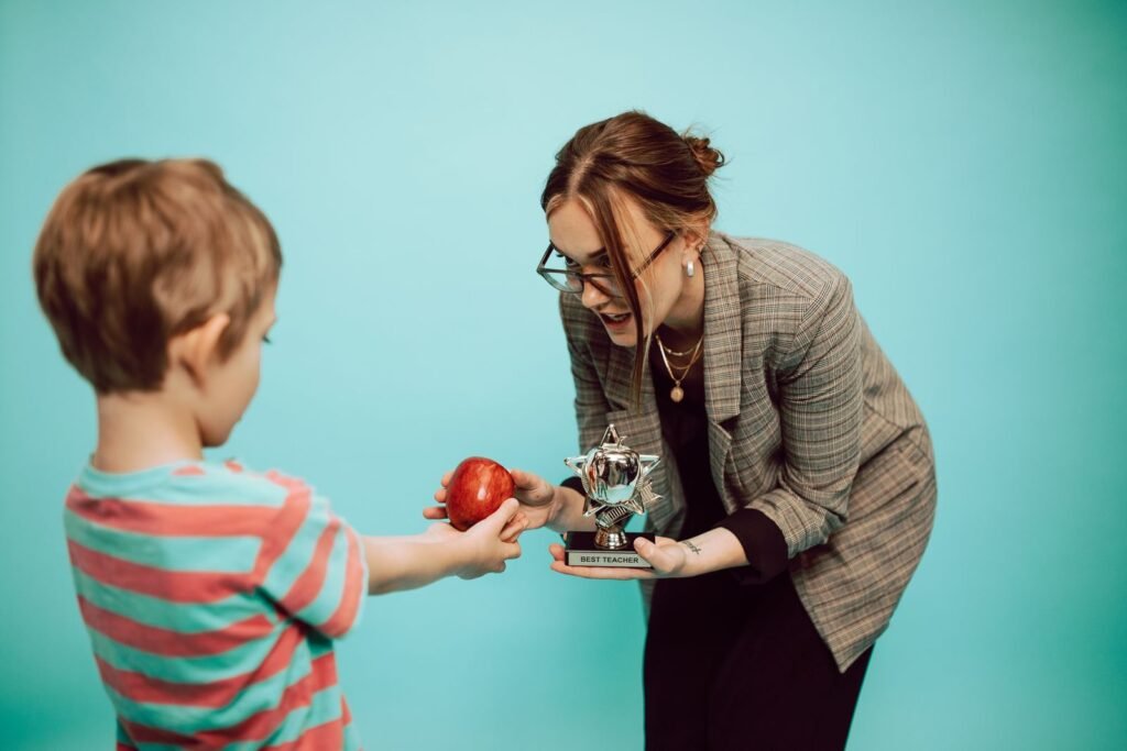 A child offers an apple to a teacher holding a Best Teacher mug