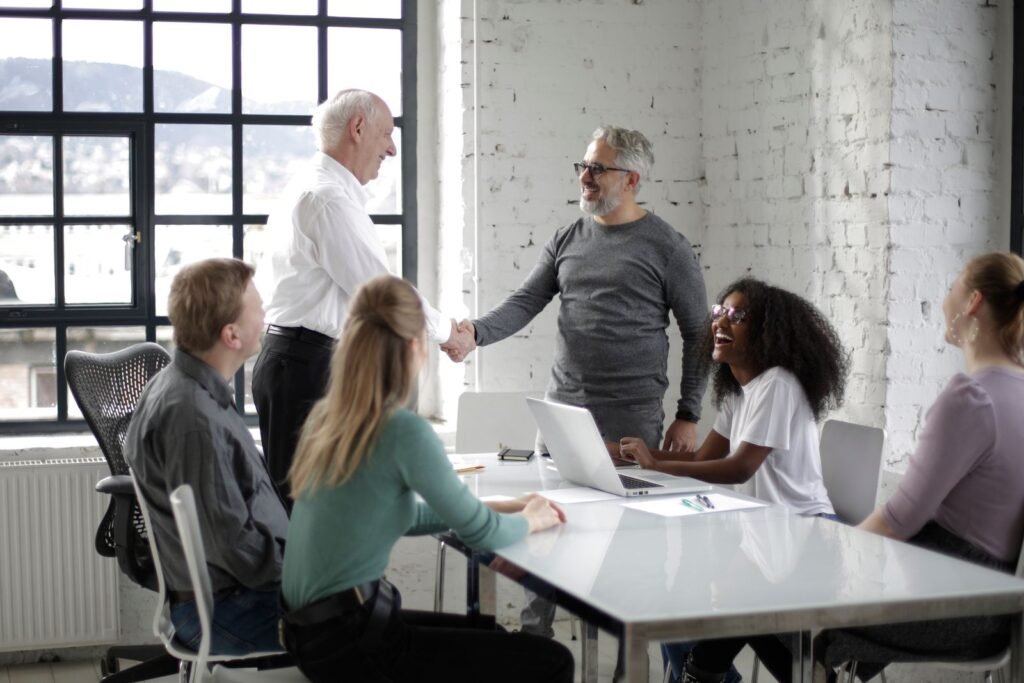 Cheerful male colleagues shaking hands while discussing business ideas