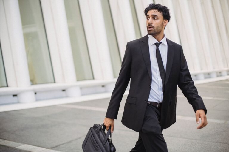 Confident businessman in corporate attire walking outside with a briefcase