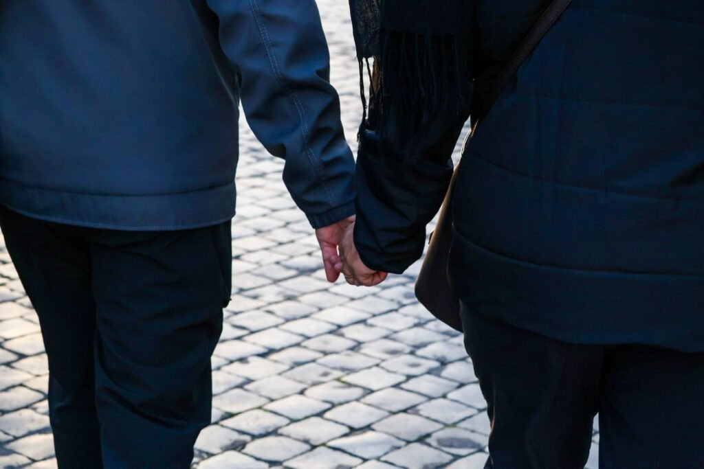 Back view of a couple holding hands walking on a cobblestone street