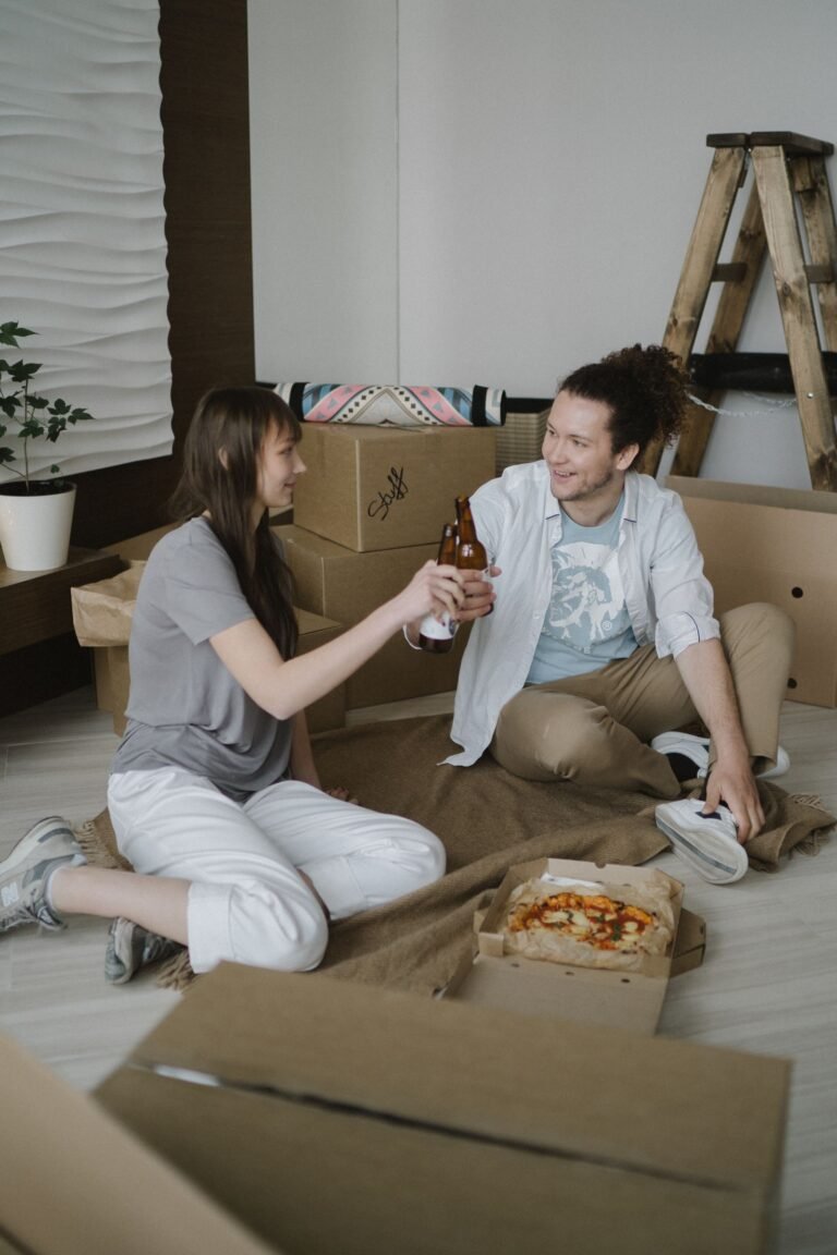 Happy couple toasting with drinks in their new apartment surrounded by moving boxes