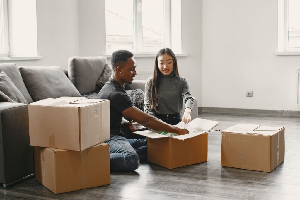Happy couple unpacking moving boxes in their new apartment living room