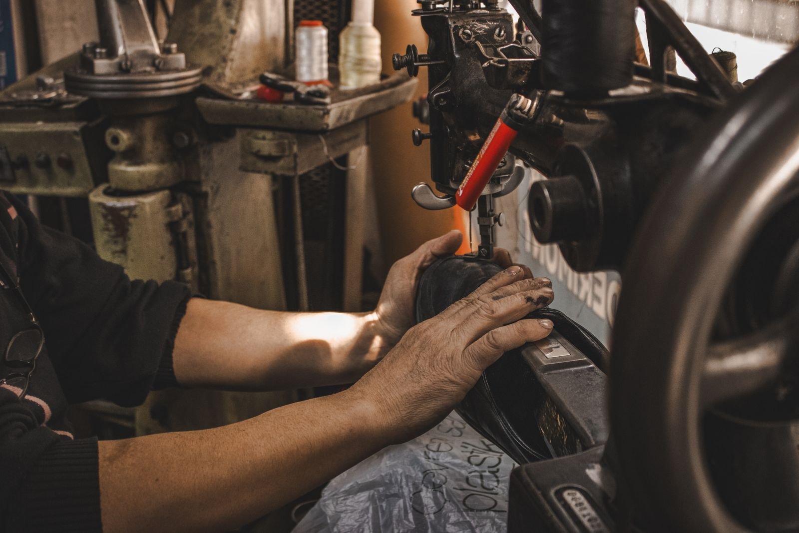 Close-up of a craftsman's hands operating a vintage industrial sewing machine