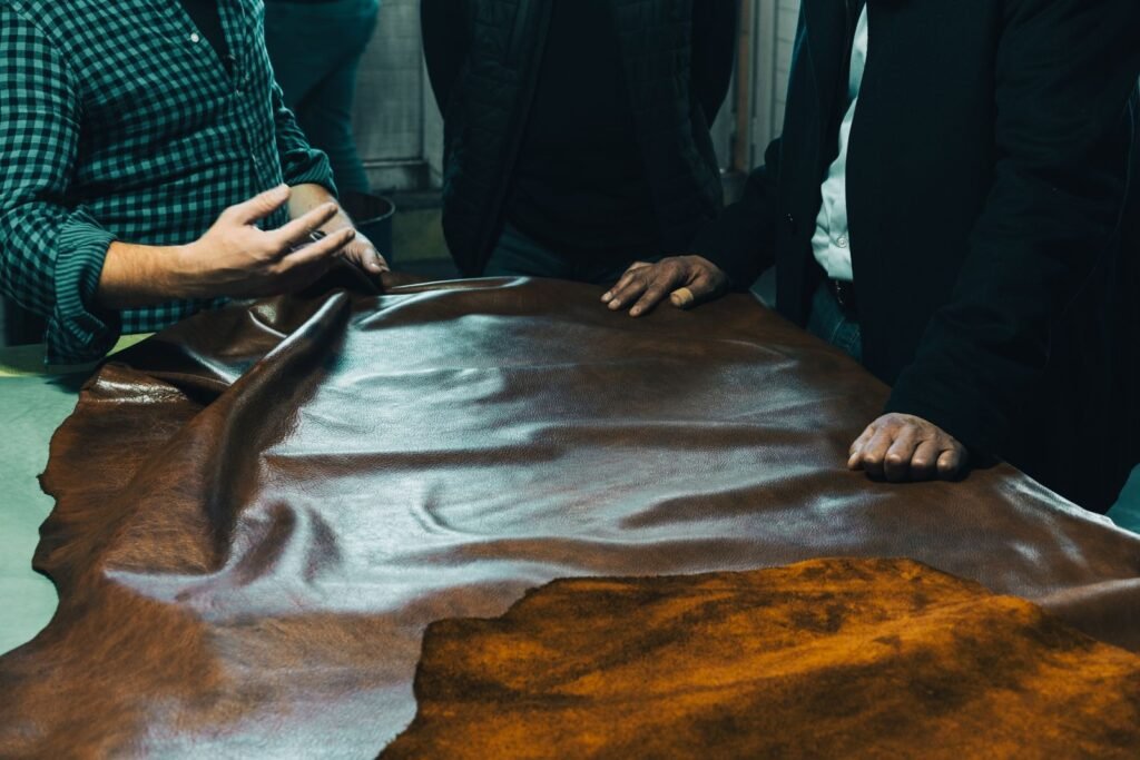 A group of craftsmen examining leather on a table in a workshop