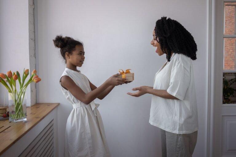 A joyful moment as a daughter gifts her mother with a present in a warmly lit room