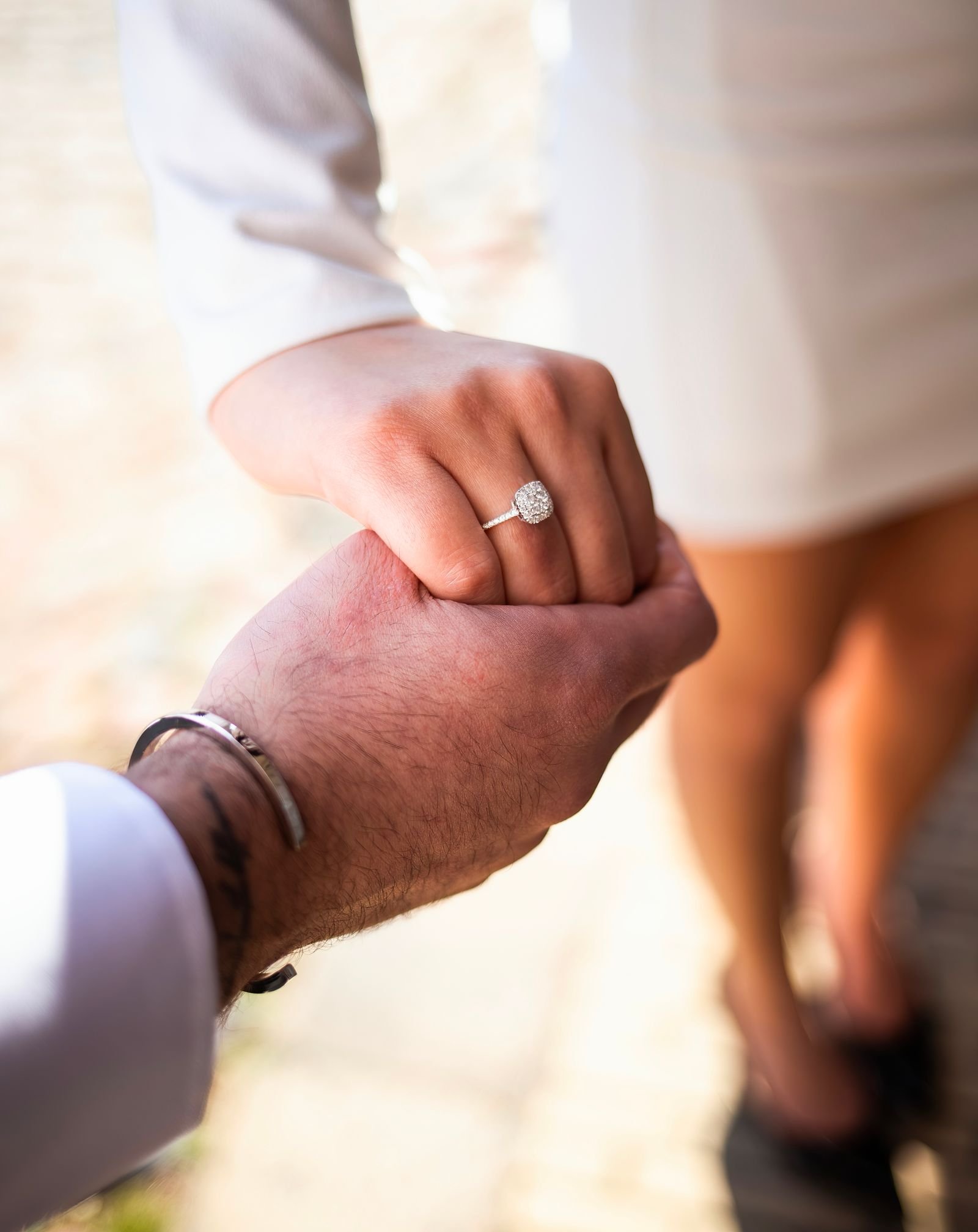 Close-up of an engaged couple holding hands with a sparkling diamond ring