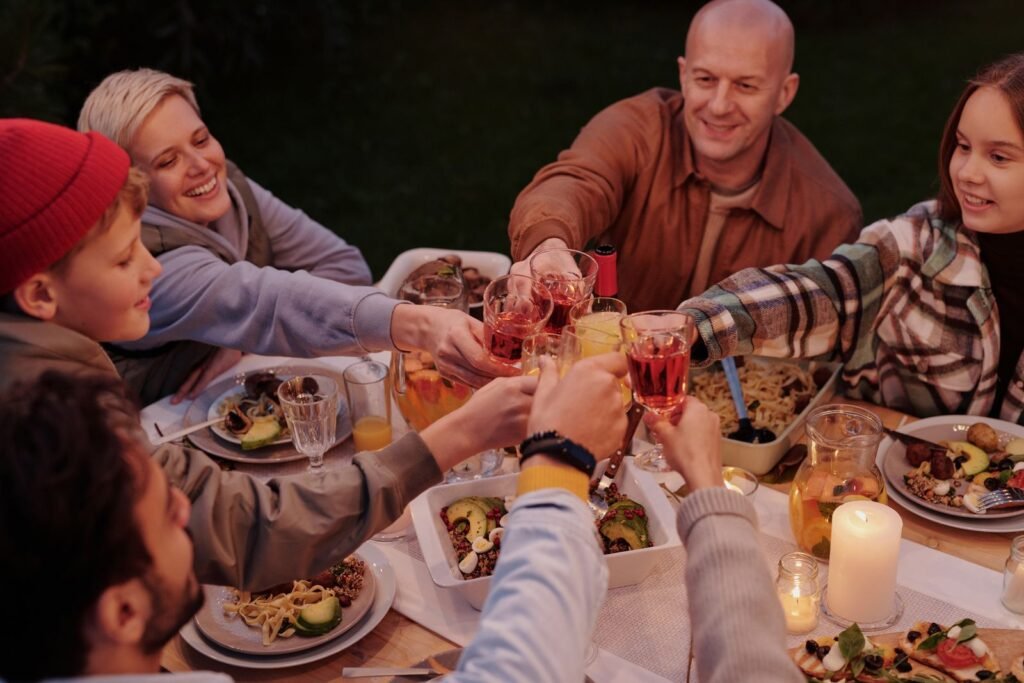 Smiling adults with children clinking glasses in a celebratory toast