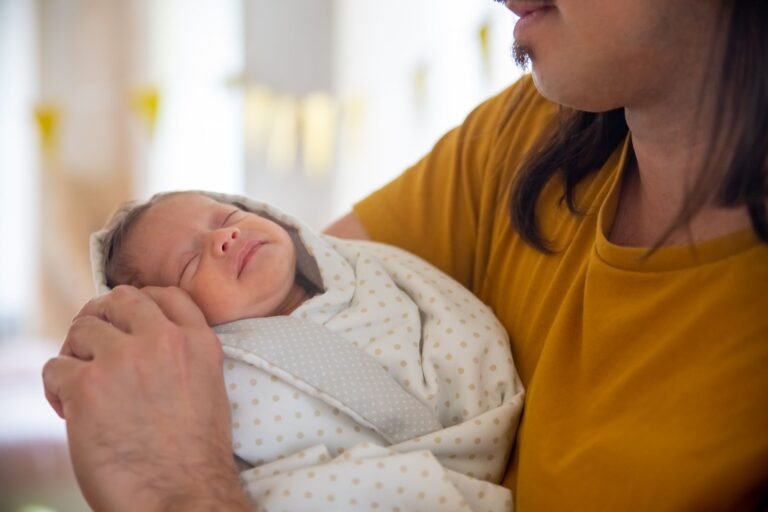 A father tenderly holding his sleeping newborn baby indoors