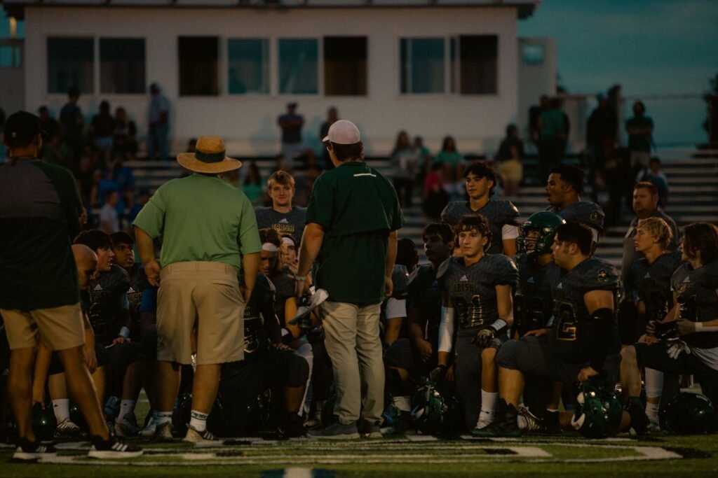 Football team huddles with coaches during a game at a stadium