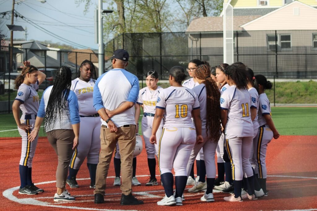 A girls' softball team gathers around their coach on the field