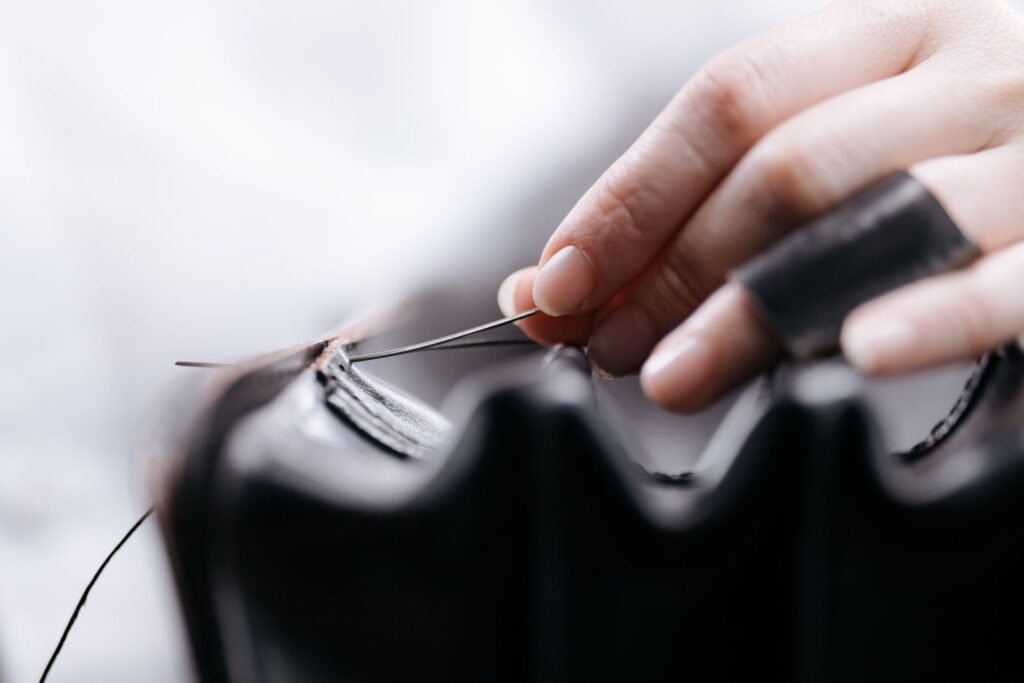 Close-up of a hand stitching leather, showcasing intricate craftsmanship