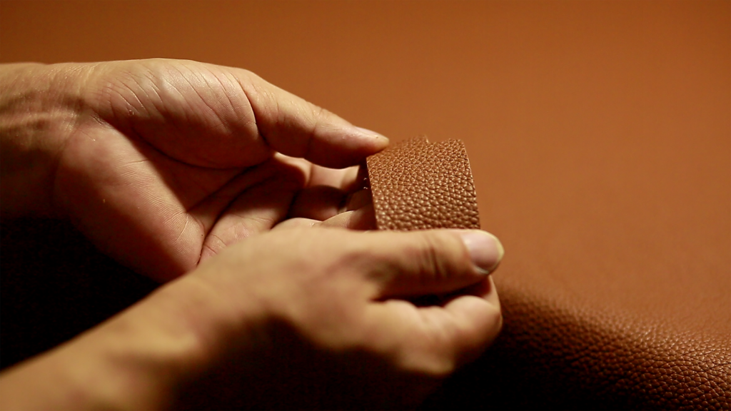 Detailed close-up of hands holding and examining textured leather material