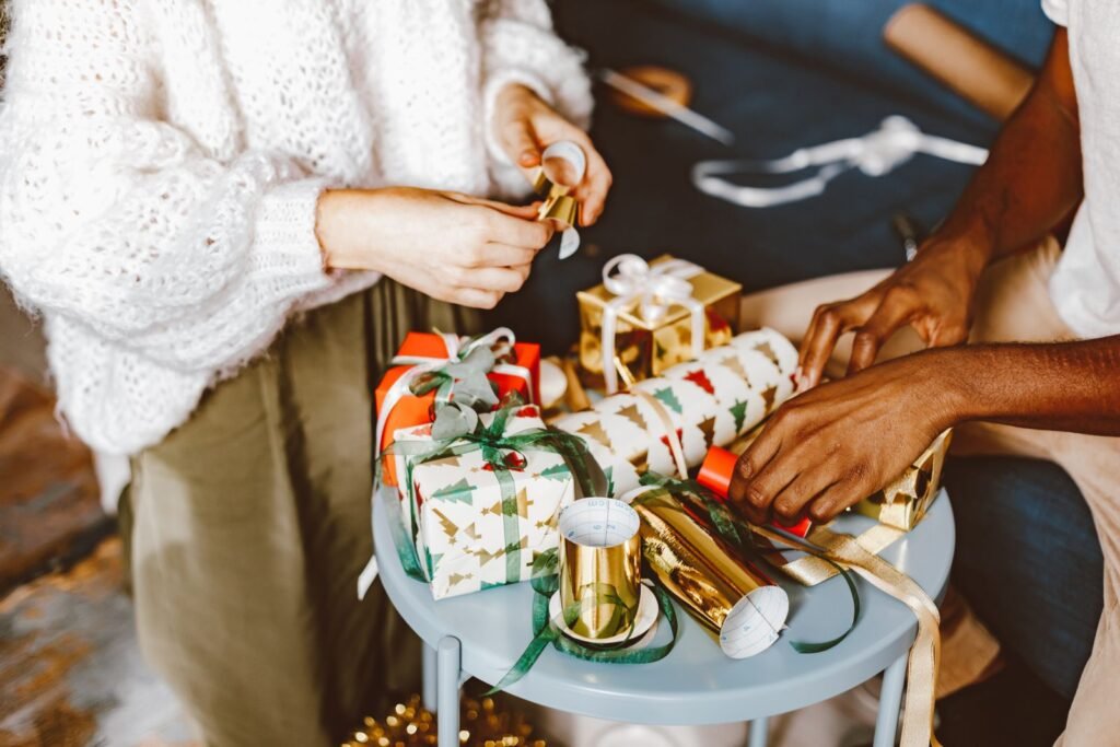 Hands wrapping Christmas gifts with bows and festive wrapping paper