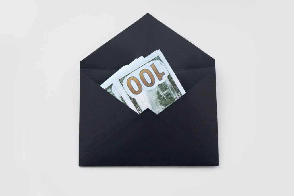 Hundred dollar bills partially visible in an open black envelope