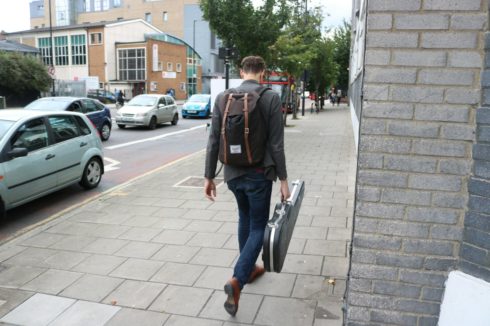Man carrying a leather briefcase while walking down a city sidewalk