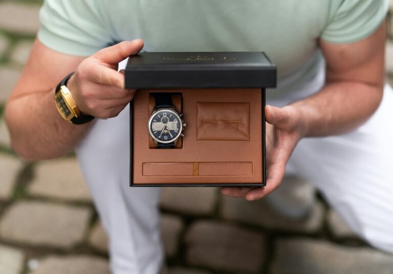 Man holding a wristwatch in its gift box, a classic retirement milestone gift