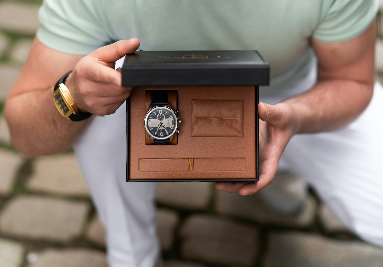Man holding a wristwatch in its gift box, a classic retirement milestone gift