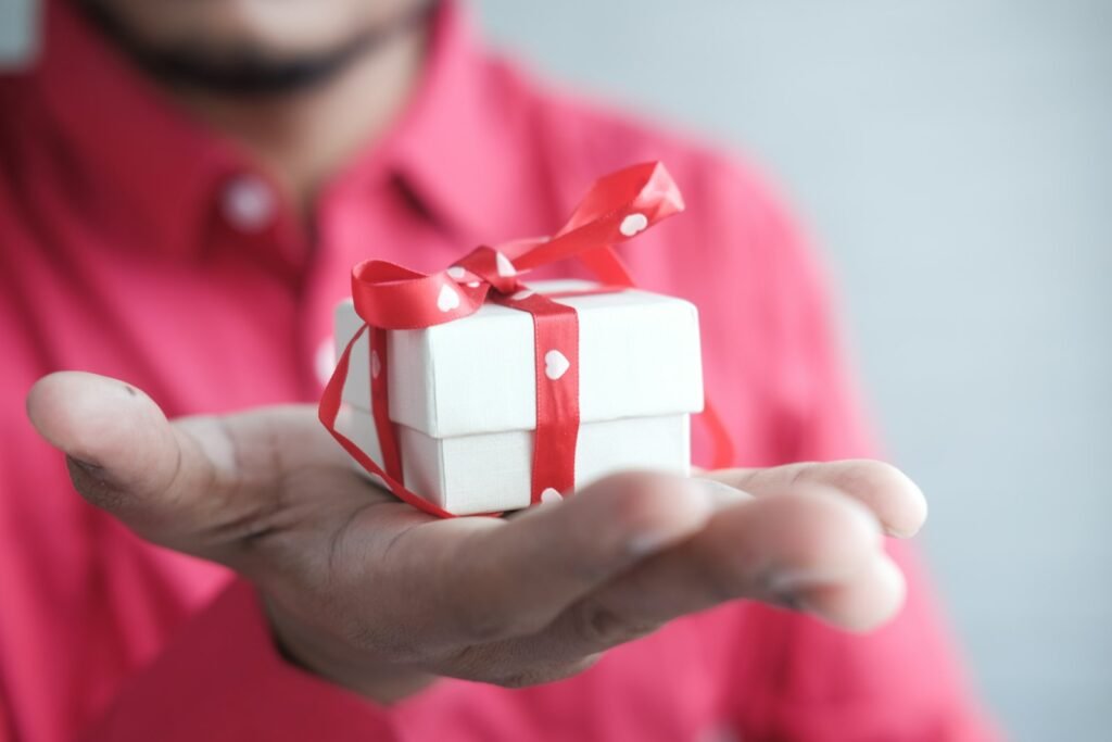 Man holding a white gift box tied with a red ribbon