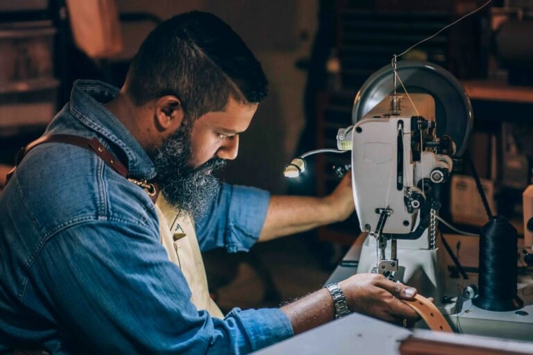 Man sewing and repairing a brown leather belt by hand