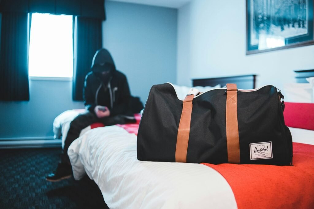 Man sitting on a bed near a black and brown duffel bag while packing