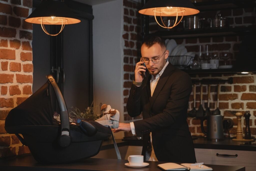 Man in a suit multitasks with a baby in a carrier while on a phone
