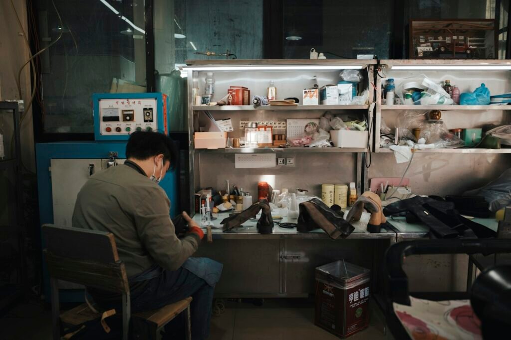 Man working at a cluttered workbench with shelves of tools above