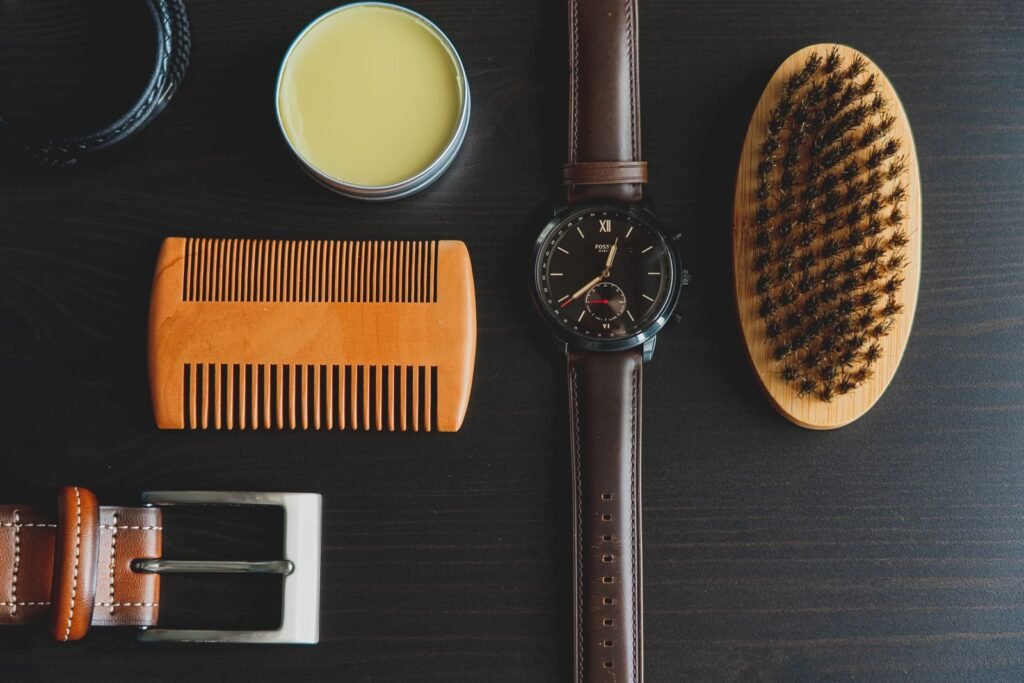 Flat lay of men's grooming accessories including watch, brush, comb, and pomade