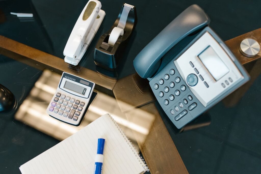 A neatly arranged office desk with a calculator, phone, and stapler