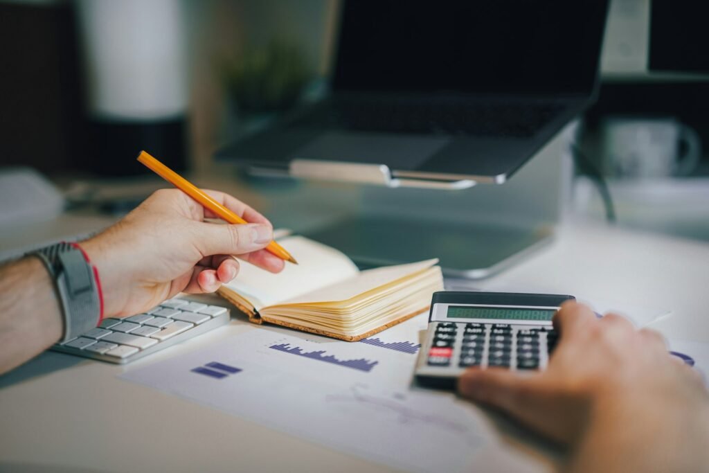 Person sitting at a desk with a calculator and a notebook