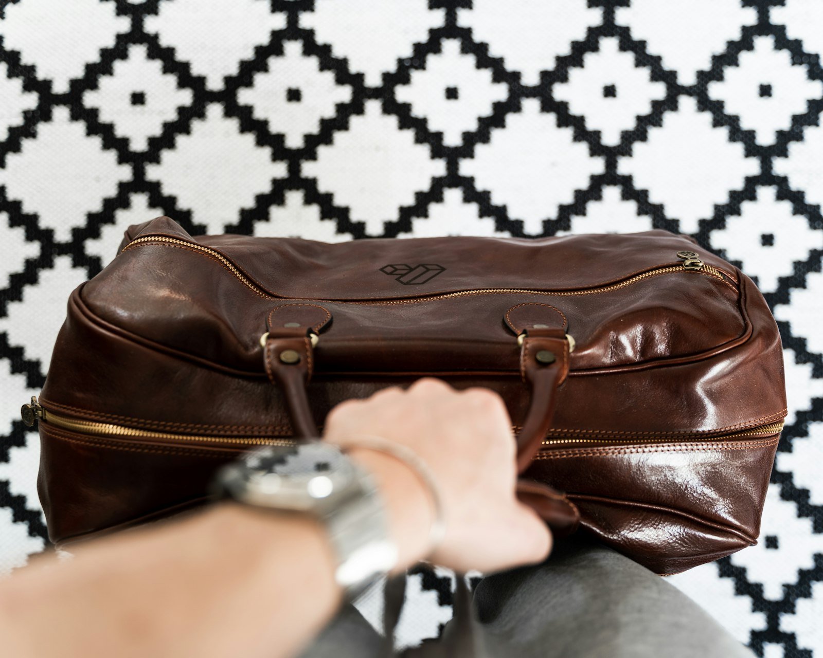 Person holding a brown leather travel bag by its handle