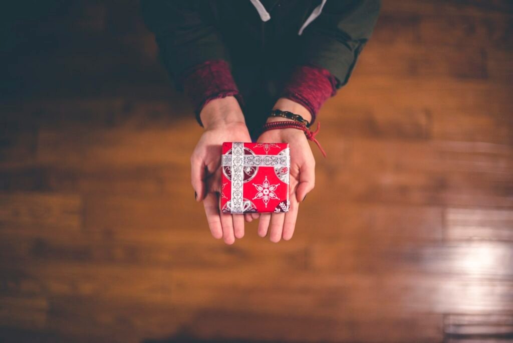 Person holding a red and white gift box