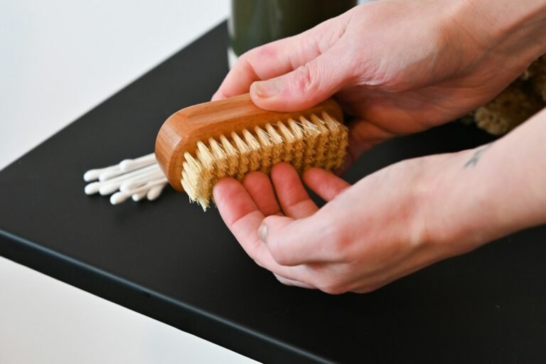 Person holding a wooden suede cleaning brush on a table