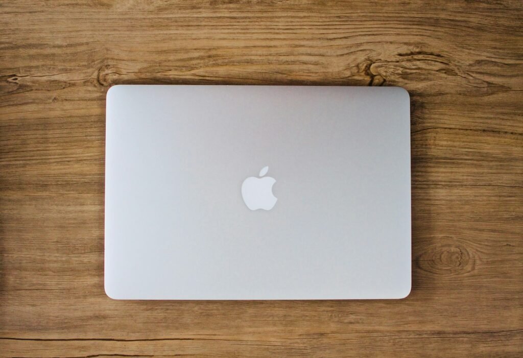 Person taking a photo of a silver MacBook on a table